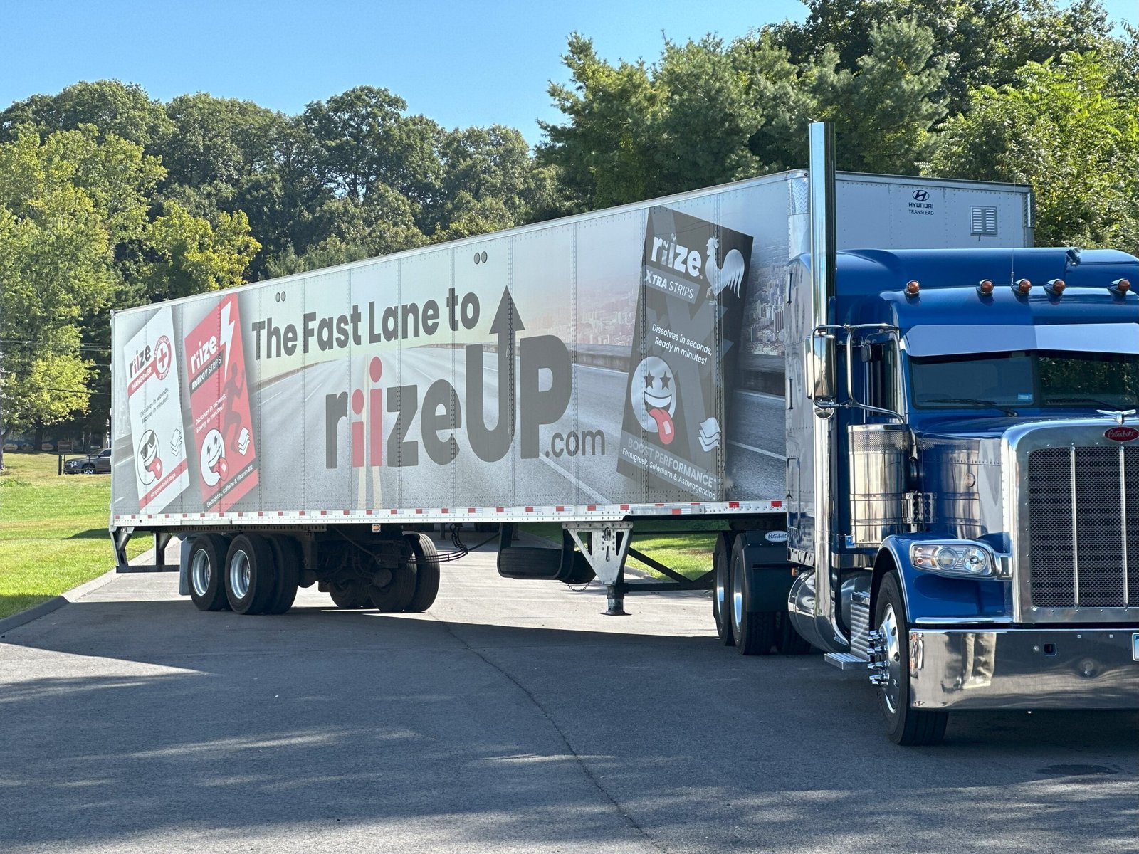 Wrapped semi truck with mobile billboard trailer driving along a local route