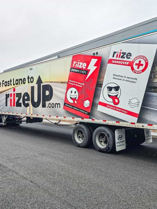 Highway truck trailer advertising Rize Up energy strips with bold graphics and product images for roadside visibility.